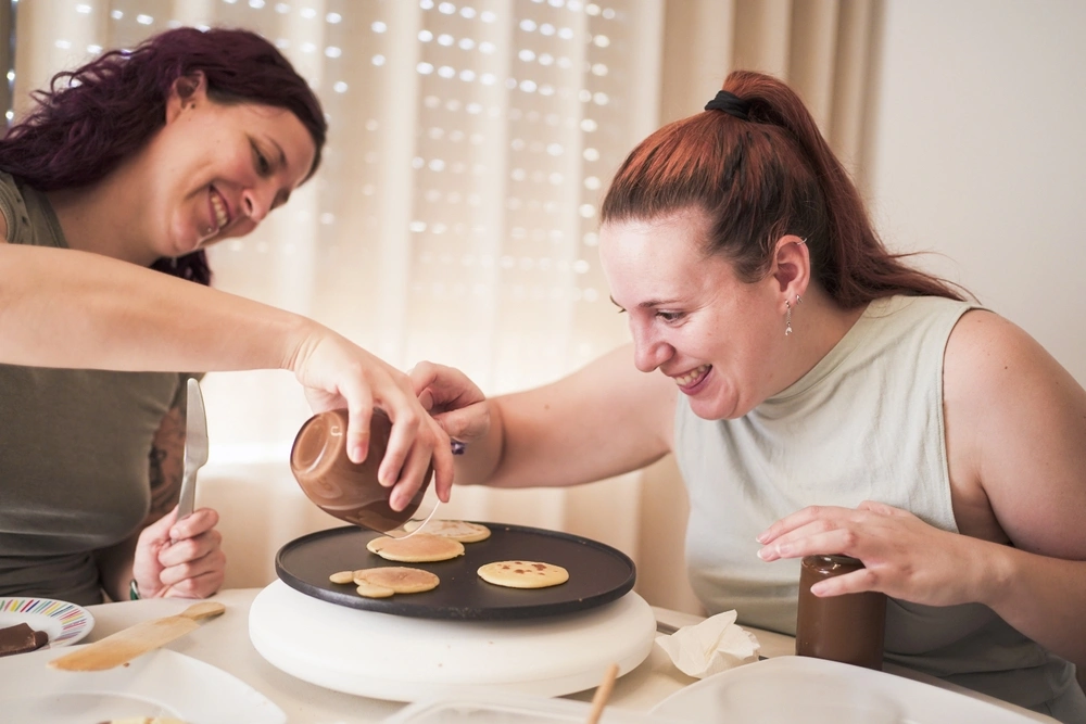 nurse helping disabled women in cooking pancakes